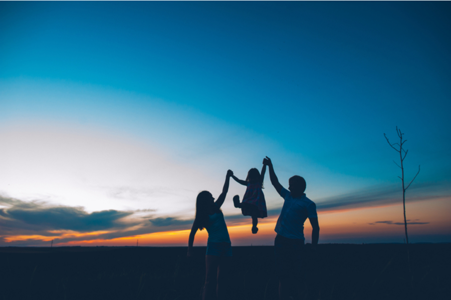 family-sunset parents holding up child at sunset